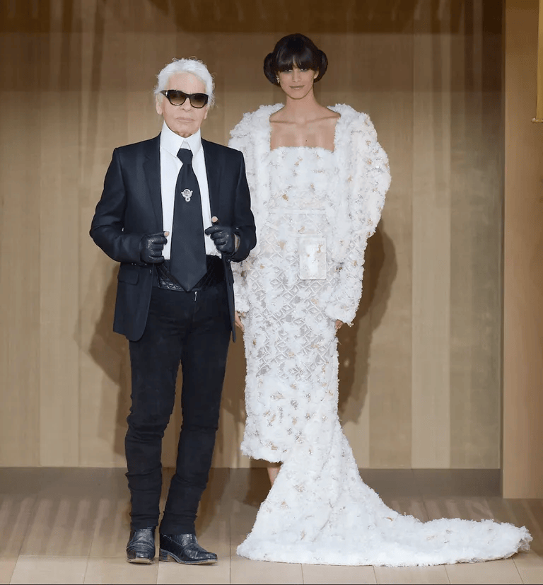 Karl Lagerfeld and model Mica Arganaraz as the Chanel bride during the finale of the Chanel Spring/Summer 2016 Haute Couture show, featuring an eco-chic textured white gown and double side buns